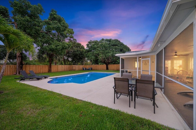 509 Oak Ter, Jupiter, FL 33458 - pool at dusk featuring a fenced backyard, a yard, a patio, and a ceiling fan