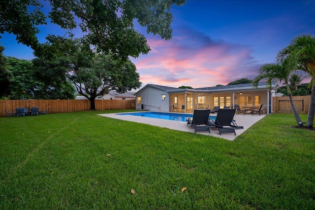 509 Oak Ter, Jupiter, FL 33458 - back of house at dusk featuring a yard, a fenced in pool, a patio, and a fenced backyard