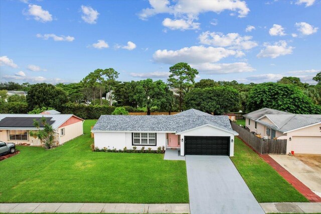 509 Oak Ter, Jupiter, FL 33458 - ranch-style house with a front lawn, driveway, fence, an attached garage, and stucco siding