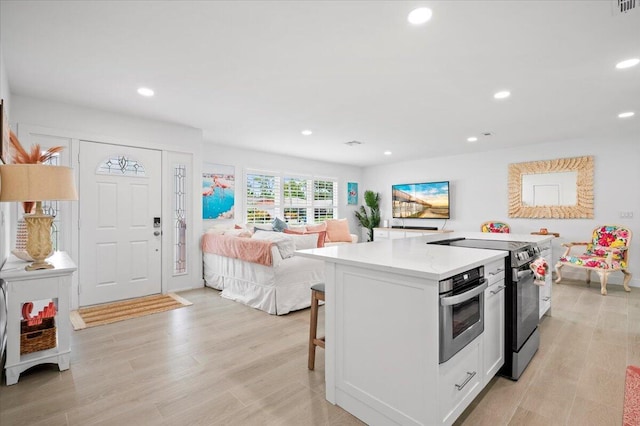 509 Oak Ter, Jupiter, FL 33458 - kitchen with open floor plan, light wood-style floors, range with electric stovetop, light countertops, and a kitchen island