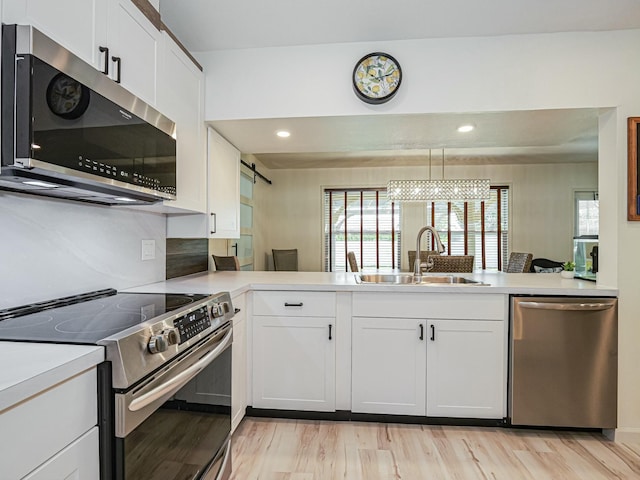 1732 Sunrise Ln, Sebastian, FL 32958 - kitchen with a peninsula, appliances with stainless steel finishes, a sink, and light wood finished floors