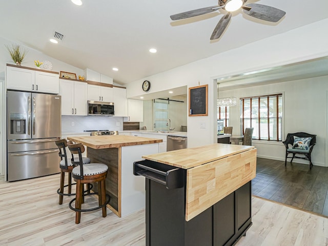 1732 Sunrise Ln, Sebastian, FL 32958 - kitchen with white cabinets, a center island, visible vents, butcher block countertops, and appliances with stainless steel finishes