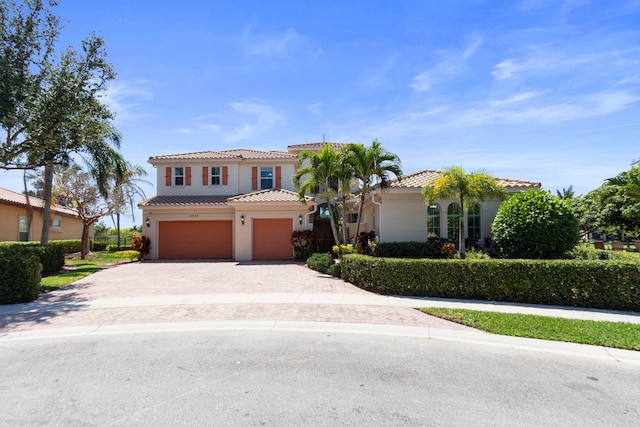 mediterranean / spanish home with stucco siding, decorative driveway, a garage, and a tile roof