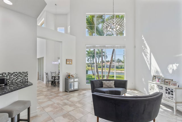 living room featuring baseboards, a water view, light tile patterned flooring, and a towering ceiling