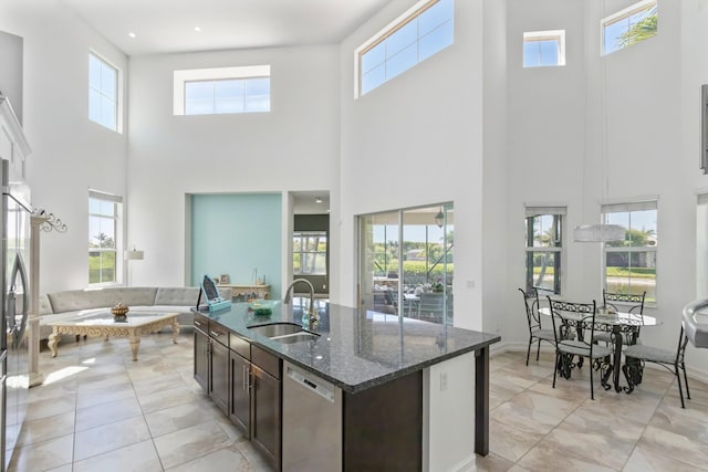 kitchen with dark brown cabinetry, a high ceiling, a sink, and stainless steel appliances
