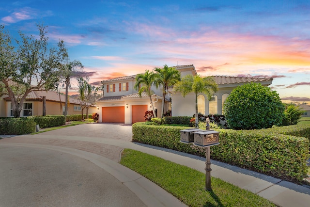 mediterranean / spanish-style house featuring a tile roof, driveway, a garage, and stucco siding