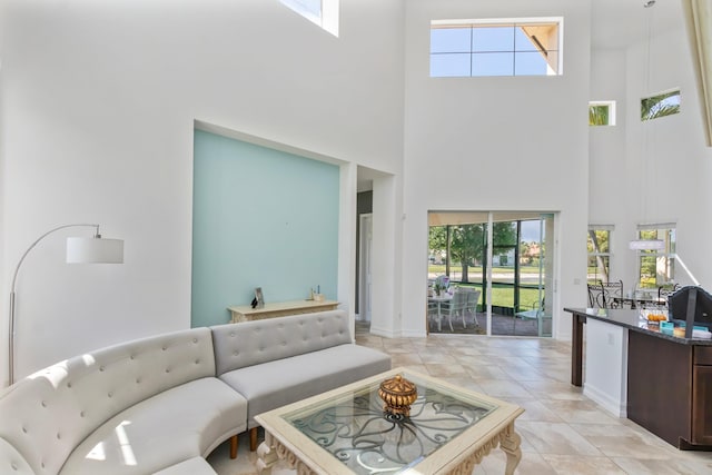 living area with light tile patterned floors, a wealth of natural light, and a high ceiling