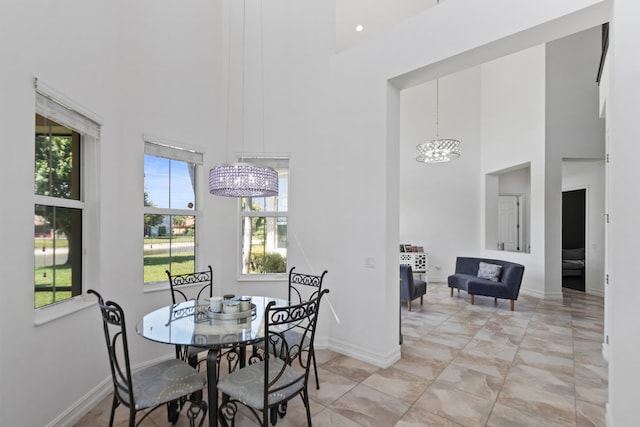 dining area with an inviting chandelier, baseboards, and a high ceiling