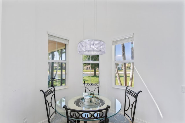 dining room with a notable chandelier, a water view, and baseboards