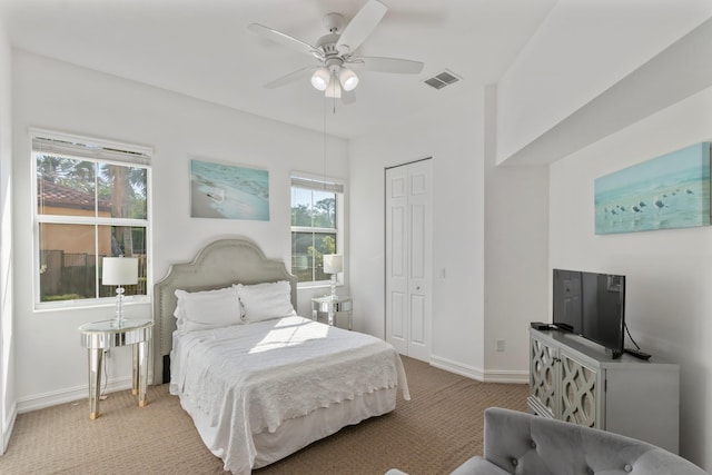 bedroom with a closet, a ceiling fan, visible vents, carpet, and baseboards