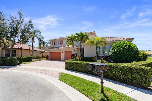 mediterranean / spanish-style home featuring stucco siding, a tile roof, driveway, and an attached garage