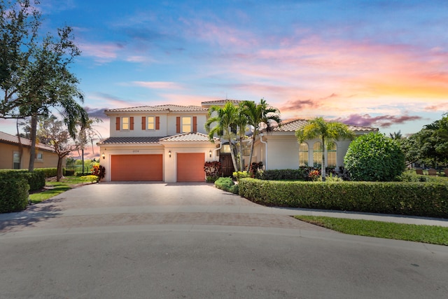 mediterranean / spanish-style home featuring stucco siding, a garage, concrete driveway, and a tile roof