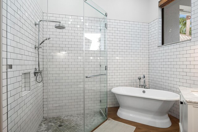 2441 NW 64th St, Boca Raton, FL 33496 - bathroom featuring a shower stall, wood finished floors, vanity, tile walls, and a soaking tub