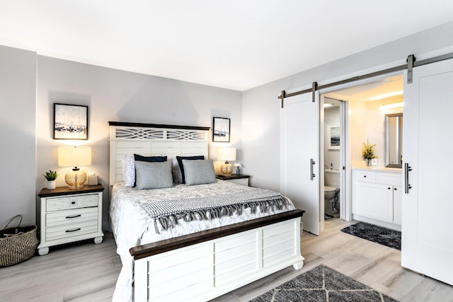 2400 Presidential Way Unit 1803, West Palm Beach, FL 33401 - bedroom featuring a barn door, light wood finished floors, and ensuite bathroom
