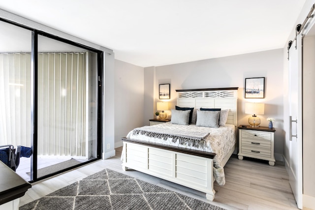 2400 Presidential Way Unit 1803, West Palm Beach, FL 33401 - bedroom featuring a barn door, light wood-style floors, and baseboards
