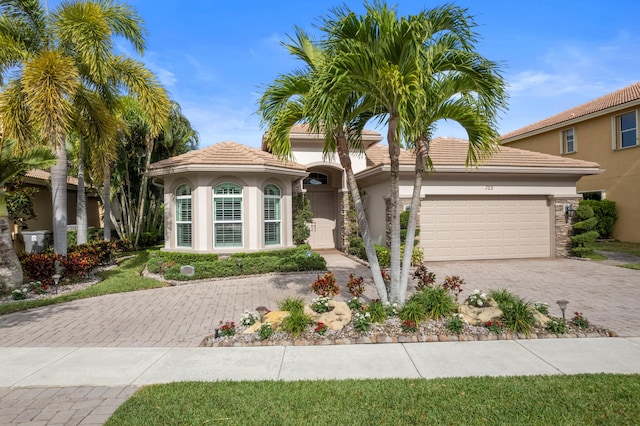 725 Edgebrook Ln, West Palm Beach, FL 33411 - mediterranean / spanish-style home with an attached garage, decorative driveway, stucco siding, and a tiled roof