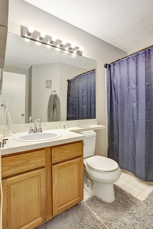 full bathroom featuring toilet, a textured ceiling, tile patterned flooring, and vanity