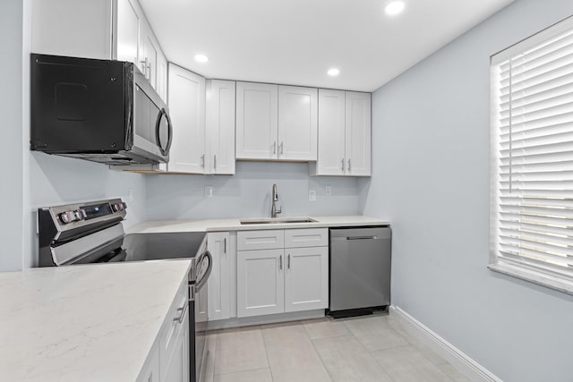 kitchen with a sink, light tile patterned flooring, stainless steel appliances, white cabinetry, and recessed lighting