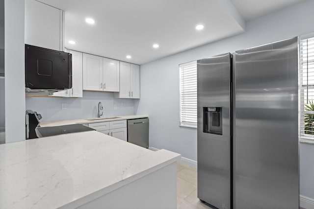 kitchen with a wealth of natural light, appliances with stainless steel finishes, a sink, and white cabinetry