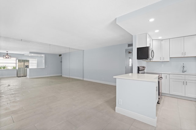 kitchen with open floor plan, white cabinetry, light countertops, baseboards, and appliances with stainless steel finishes