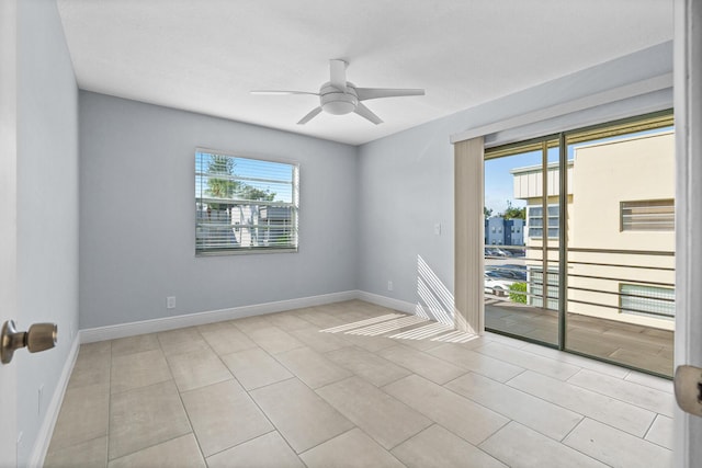 tiled empty room featuring a ceiling fan and baseboards