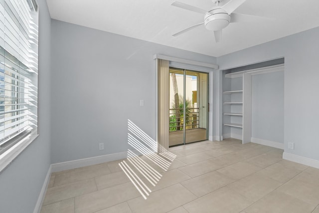 empty room with a ceiling fan, baseboards, and light tile patterned floors