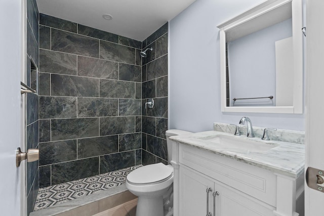bathroom with a tile shower, toilet, and vanity