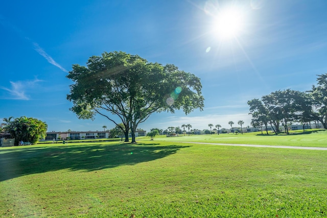 view of community featuring view of golf course and a yard