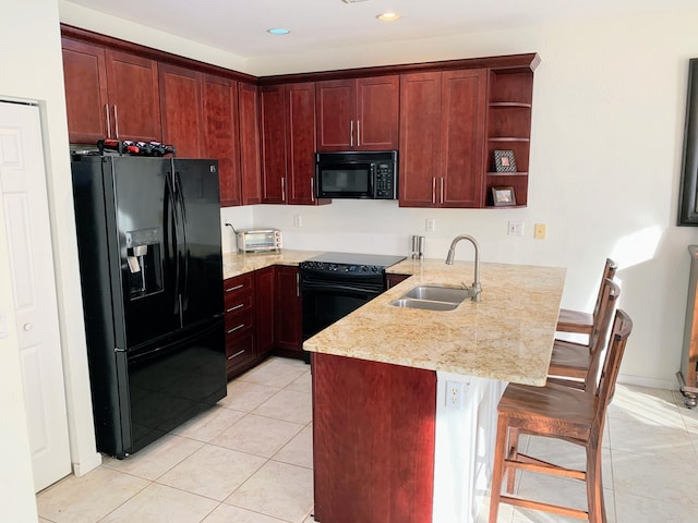 kitchen featuring a sink, light tile patterned floors, black appliances, and a peninsula