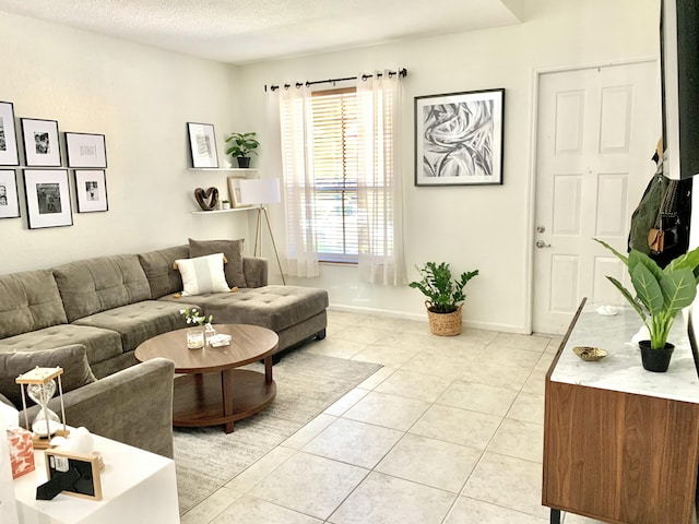 living room featuring light tile patterned flooring, a textured ceiling, and baseboards