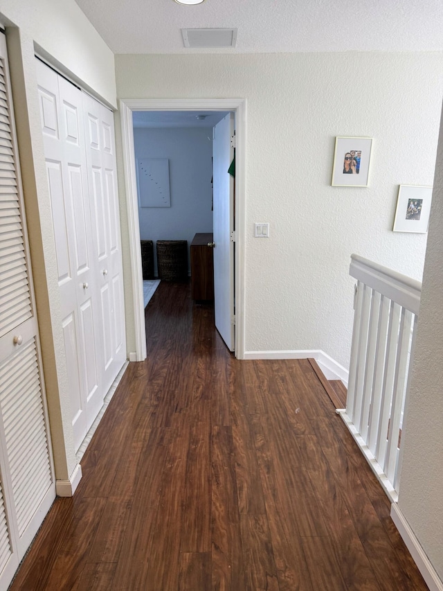 corridor with dark wood-type flooring and baseboards