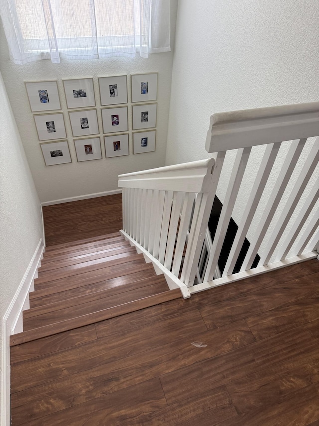 staircase with a textured wall and wood finished floors