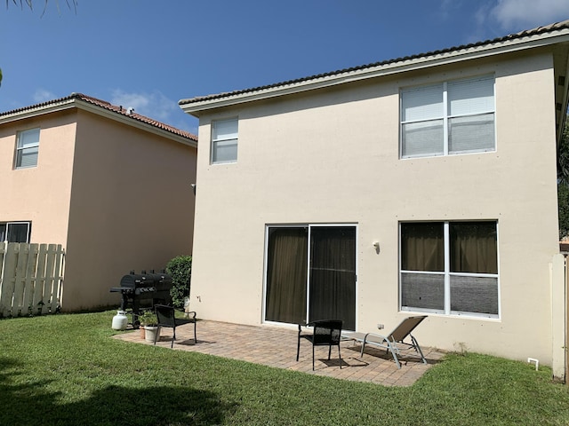 rear view of property featuring stucco siding, a patio area, fence, and a yard