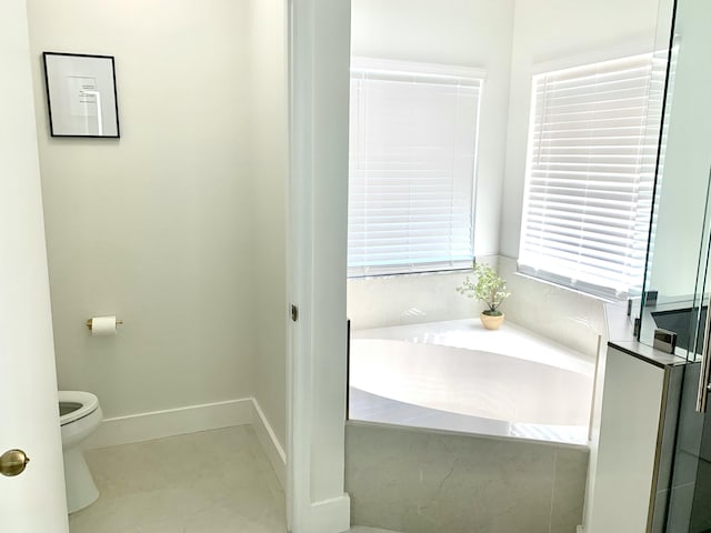 bathroom featuring toilet, baseboards, and a bath