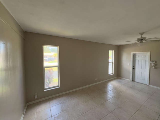 spare room with baseboards, ceiling fan, and light tile patterned floors