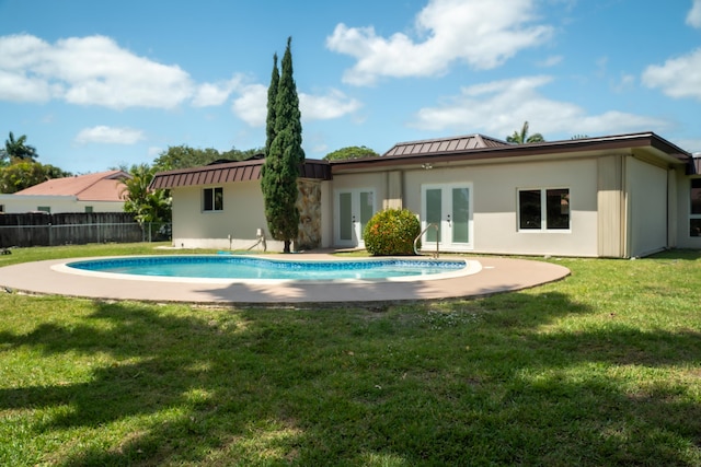 rear view of property featuring fence, a yard, a fenced in pool, and french doors