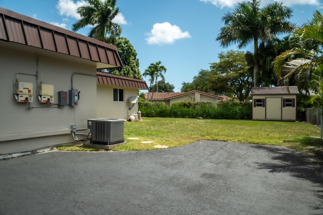 view of yard featuring a shed, a patio area, central AC, and an outbuilding