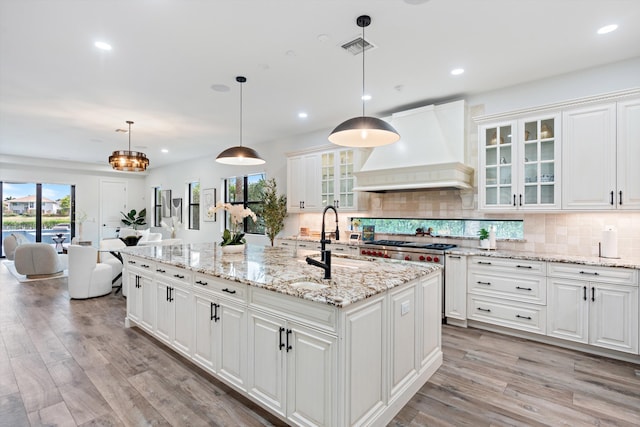 10343 S Barnsley Dr, Parkland, FL 33076 - kitchen with premium range hood, light wood finished floors, backsplash, white cabinetry, and recessed lighting