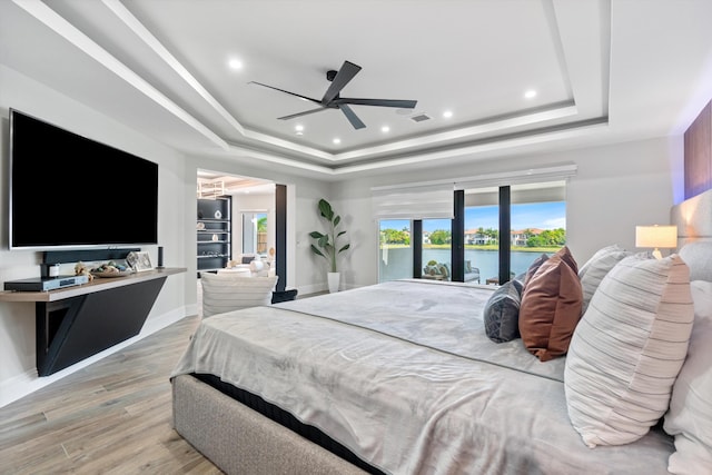 10343 S Barnsley Dr, Parkland, FL 33076 - bedroom with a raised ceiling, light wood-style flooring, a water view, recessed lighting, and access to exterior