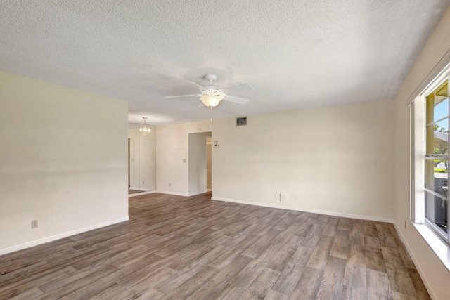 903 Savannas Point Dr Unit D, Fort Pierce, FL 34982 - empty room with wood finished floors, visible vents, baseboards, a textured ceiling, and ceiling fan with notable chandelier