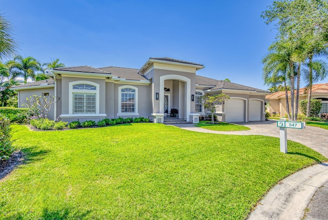 mediterranean / spanish home featuring a garage, stucco siding, driveway, and a front lawn