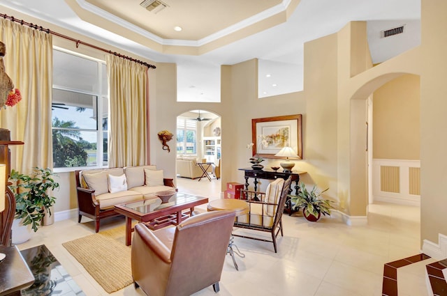 living room with visible vents, arched walkways, a raised ceiling, and a healthy amount of sunlight