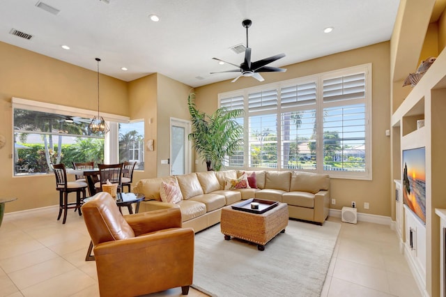 living room featuring light tile patterned floors, a wealth of natural light, ceiling fan with notable chandelier, and visible vents