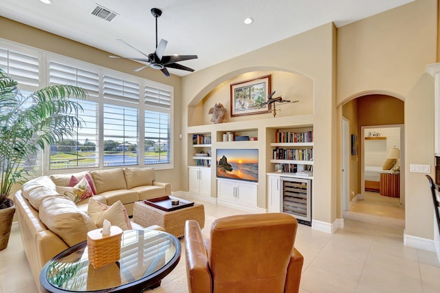 living area with visible vents, beverage cooler, built in shelves, a ceiling fan, and light tile patterned floors