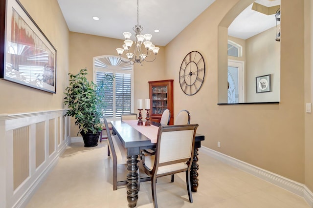 tiled dining space with arched walkways, baseboards, a notable chandelier, and recessed lighting