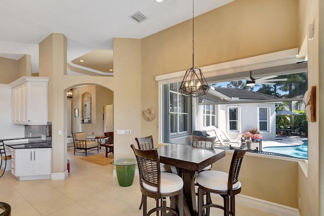 dining room with visible vents, a towering ceiling, arched walkways, baseboards, and a notable chandelier