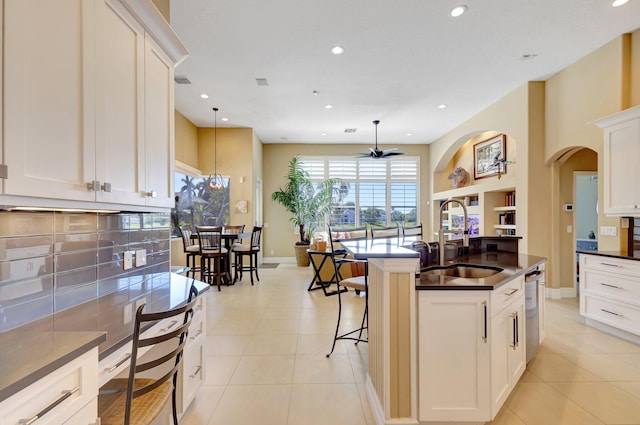 kitchen with light tile patterned flooring, dark countertops, recessed lighting, a sink, and dishwasher