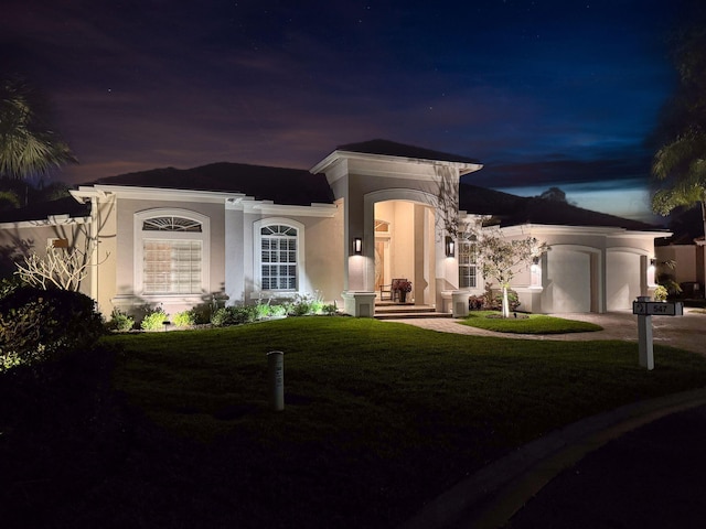 view of front of home featuring an attached garage, stucco siding, a yard, and driveway