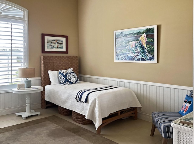 bedroom featuring tile patterned flooring and wainscoting
