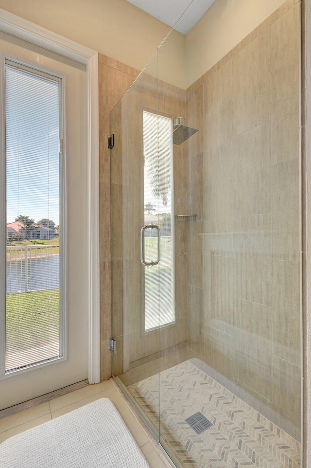 bathroom with a water view, tile patterned floors, and a shower stall
